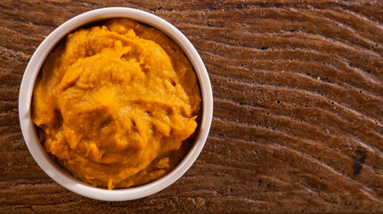 Pumpkin puree or hummus on a rustic wooden table. Selective focus