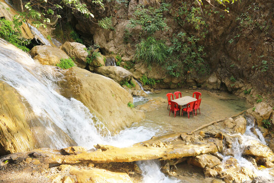 Tables and chairs of outdoor cafes in the waters of the waterfall. Romantic place in the Indian jungle. Waterfall in Rishikesh, India.