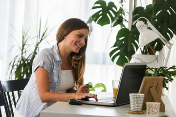 Smiling Pregnant Woman Shopping Online with Laptop Computer at Home