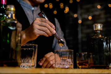 Waitress man standing pours whiskey into a glass 