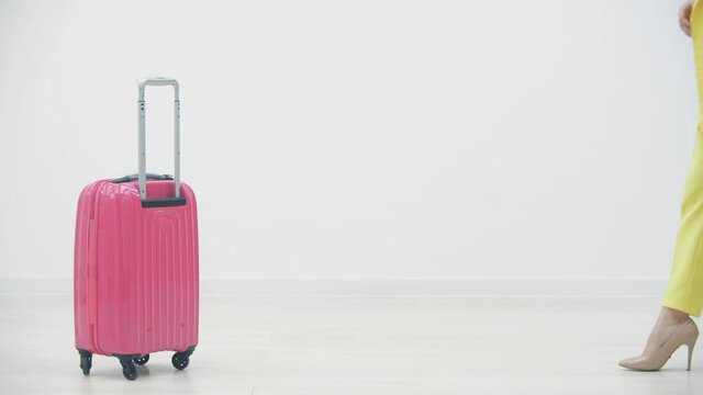 Cropped slowmotion video of female carrying a suitcase and passport over white background with copyspace.