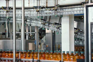 Plastic bottles with juice on conveyor line or belt in modern beverage factory.