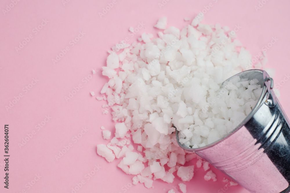 Wall mural sea salt in a tin bucket on pink background for seasoning or preserving food