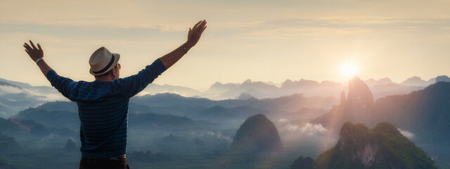 Traveller businessman raise up hand freedom and enjoy view of beautiful landscape mountains hill with fog over sunrise sky in the morning. Travel or Freedom concept.