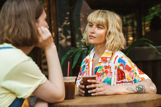 Image of two women talking and drinking soda while sitting at table