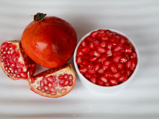 Fresh red color pomegranate fruit  and kernels in a white background