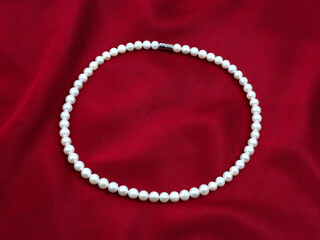 Pearl necklace on silk texture satin velvet material