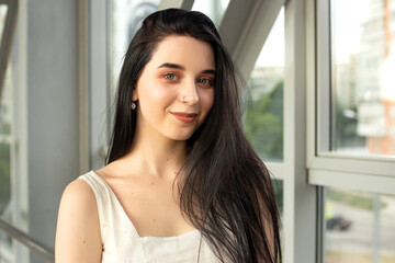 Portrait of a beautiful brunette in a light dress on the street in a pedestrian crossing on a summer day
