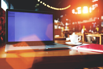 Open laptop computer with blank copy space screen for information content or text message,portable net-book and cup of drink lying on table in contemporary coffee shop interior, freelance workspace