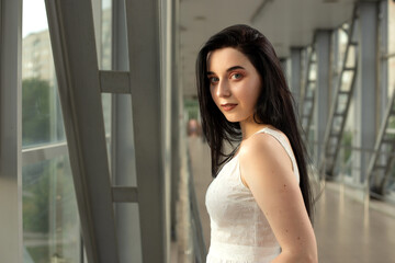 Portrait of a beautiful brunette in a light dress on the street in a pedestrian crossing on a summer day