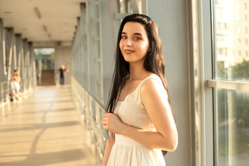 Portrait of a beautiful brunette in a light dress on the street in a pedestrian crossing on a summer day