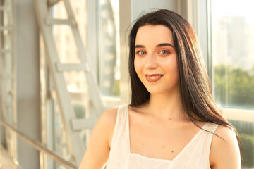Portrait of a beautiful brunette in a light dress on the street in a pedestrian crossing on a summer day