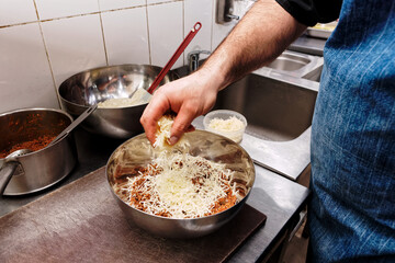 Chef is mixing ground meat with bechamel sauce and cheese