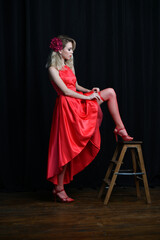 beautiful girl in evening red dress posing on a black background