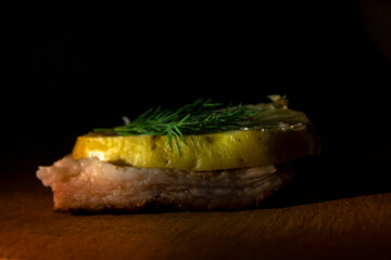 Sandwich, lard and on top potatoes with fried skin and on top parsley in the rays of light