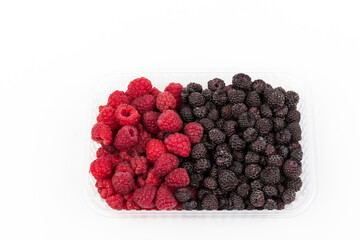 Fresh black and red raspberry in  plastic container isolated on white background. Berry in close-up