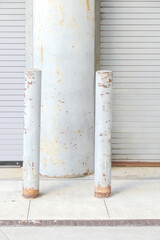 Weathered concrete column behind rusty posts