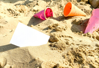 on the sand lies a white business card on the background of toys for children