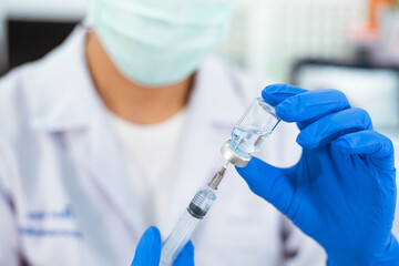 Doctor in blue glove filling syringe with vaccine