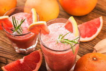 Grapefruit juice with rosemary and ice in a glass on the table. Refreshing summer cocktail