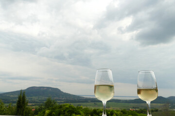 Two glasses of fine riesling wine in the Badacsony region in Hungary with volcanic hill Badacsony in the background