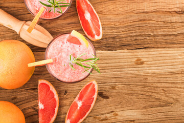 Grapefruit juice with rosemary and ice in a glass on the table. Refreshing summer cocktail