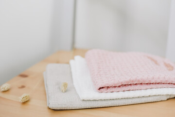 Pile of clean linen cotton towels on kitchen table. Pastel colors. Food photo. Natural linen cotton fabric. Rustic farmhouse style