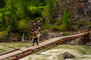 Obraz na płótnie Canvas Old suspension bridge over a mountain river. Chuya, Altai