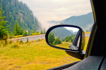 Car side mirror with a beautiful reflection of the landscape during road trip in the mountains