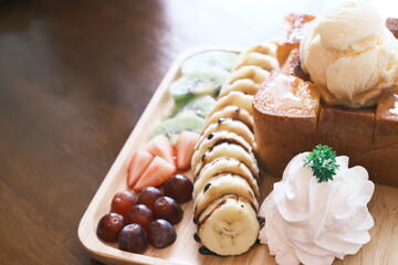 Delectable dessert with honey toast on top by ice cream and various fruits. close up, selective focus