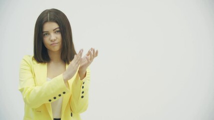 Pretentious brunette woman in yellow formal suit clapping, and looking annoyed over white background