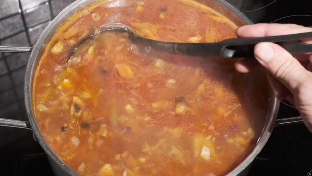 Shef Cooks and mixing Healthy vegetable tomato soup food in bowl in kitchen. Close up POV