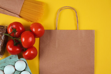 Flat lay with food donations and paper bag on yellow background with copyspace, mockup. Pasta,...