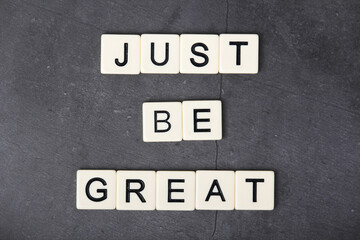 A motivational quote Just be great formed with tile letters