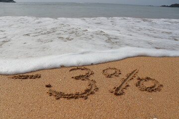 The inscription minus three percent on the sand near the ocean. Discount on vacation at the beach.