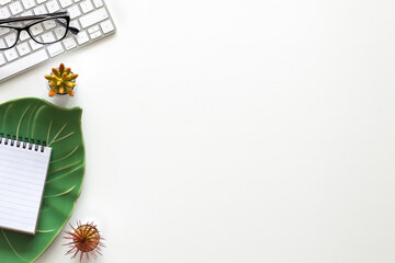 White copy space with keyboard and ceramic monstera leaf.