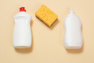 Bottles of dishwashing liquid and sponge on a beige background.