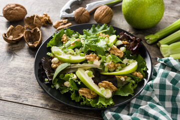 Fresh Waldorf salad with lettuce, green apples, walnuts and celery on wooden table.	