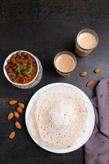 Appam, Kerala breakfast food  Kadala curry or hot and spicy chickpea Masala and milk tea chai, christian  breakfast on dark black background.  fermented rice pan cake. Top view of Indian veg food.