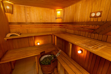 Interior of Finnish sauna, classic wooden hot sauna. Finnish bathroom with steam. Tubs with oal brooms.