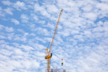 Fototapeta na wymiar Yellow metal crane is working to construct the building for urban growing business. It seems the Isolate single object on the beautiful blue sky and white clouds as background with copy space.