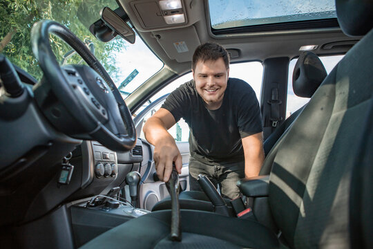 Man Cleaning Inside Car With Vacuum Cleaner