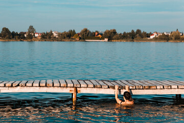 Fototapeta na wymiar woman in swimsuit at wooden pier. resting at lake