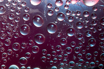 Maroon-malachite bubbles are located in the water on a burgundy background and are lit by the rays of the bright sun. Close-up. 