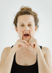 Cute girl doing face yoga exercises, stretching and strengthening the muscles of the face. The concept of non-surgical rejuvenation and self-care.