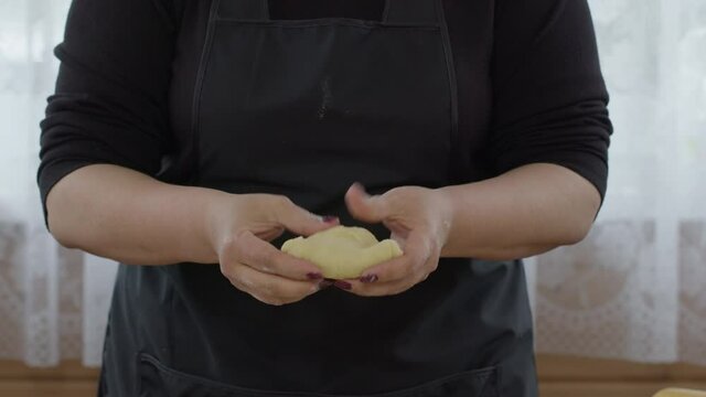 Female baker cooking buns in kitchen. Woman baker cooking ball of baking dough, making dough for dumplings, empanadas. Bakery products, homemade pastries, biscuit, pies, loaf, recipe concept