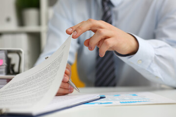 Cropped photo of young businessman holding a pen and signing a document in office