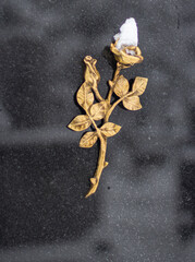 Goldene Rose auf Grabstein mit Schnee