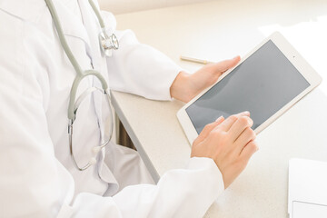 Online visit to doctor. doctor in white coat looks at tablet, sitting at table, free space