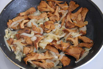 Fried chanterelles (roosters) with onions in a pan